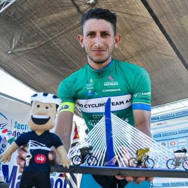 Vitor Gustavo no pódio com troféu, uniforme Pro Cycling Team ADF